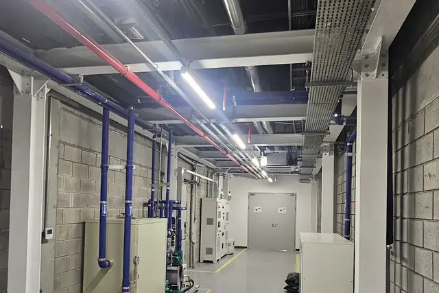 Corredor técnico com tubulações azuis e eletrocalhas
