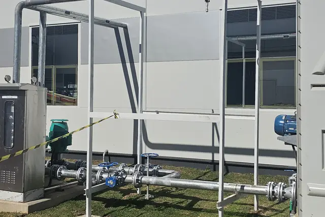 Tubulações e bomba em estrutura metálica junto ao galpão