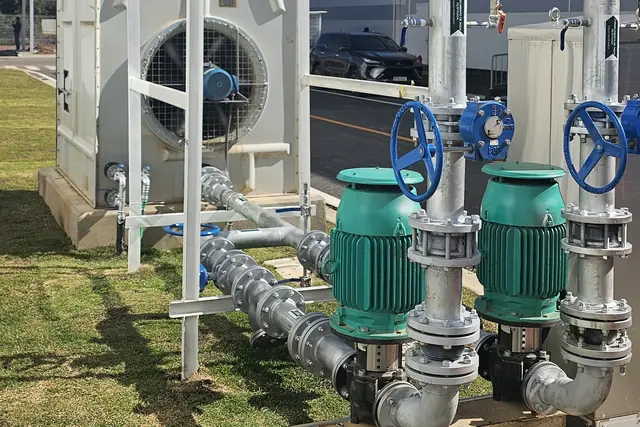 Bombas verdes com válvulas e tubulação junto a torre de resfriamento