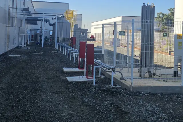 Pátio com tubulações em apoios metálicos e tanques